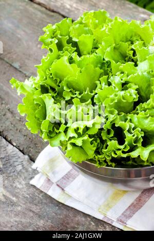 Fresche foglie di lattuga nel recipiente di metallo sul vecchio tavolo in legno nel giardino Foto Stock