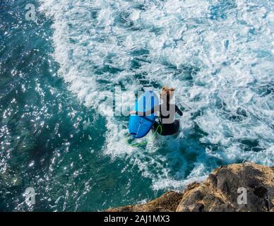 Vista aerea del surfer il salto in mare dalle rocce. Foto Stock