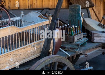 Un vecchio barrow nel fienile con una bilancia e vecchie bottiglie Foto Stock