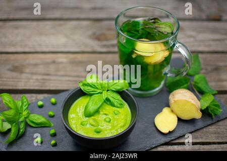 Crema di piselli con basilico sul nero ardesia. Con la menta - tè allo zenzero. Foto Stock