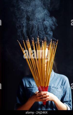 Giovane donna cinese pregando con grande bruciare bastoncini di incenso nelle sue mani, Ah Hoi Chuong Quan Pagoda, Ho Chi Minh City, Vietnam, Indocina, Asia Foto Stock