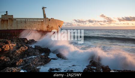 Abbandonata la nave nel mare in tempesta con grandi onde di vento durante il tramonto. Foto Stock