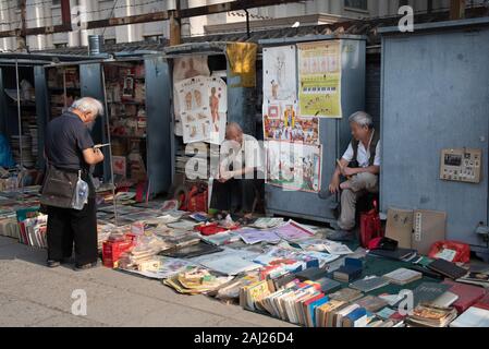 Il cinese uomo asiatico la lettura e la vendita di libri antichi a Panjiayuan pulci Mercato di antiquariato a Beijing in Cina. Foto Stock