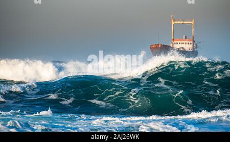 Abbandonata la nave nel mare in tempesta con grandi onde di vento durante il tramonto.3 Foto Stock