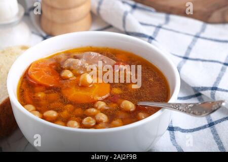 Zuppa di pollo, piselli, pomodoro e le carote affettate. Gustosa zuppa calda. Foto Stock