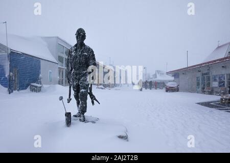 Blizzard a Longyearbyen, statua di un minatore di carbone nella neve. Svalbard, Norvegia Foto Stock