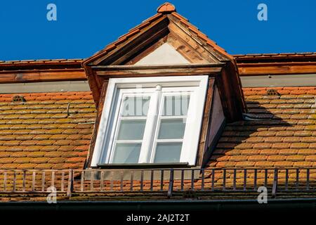 Dormer su un tetto con griglia di neve e cielo blu Foto Stock