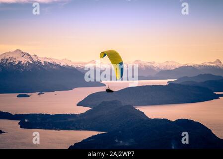 Parapendio oltre Nahuel Huapi lago e montagne di Bariloche in Argentina, con vette innevate sullo sfondo. Concetto di libertà, avventura, battenti Foto Stock