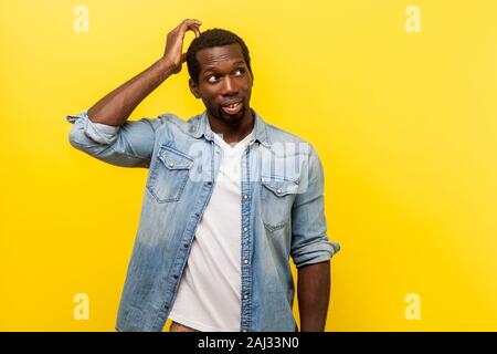 Dubbio, hanno bisogno di pensare. Ritratto di incerta giovane uomo in denim Camicia casual guardando in alto, graffiare la testa mentre pensando con confuso faccia perplesso. ind Foto Stock