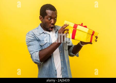 Da lungo tempo atteso regalo! Ritratto di piacevolmente sorpreso uomo in denim Camicia casual disimballaggio presente, guardando all'interno della scatola con la curiosa espressione stupita Foto Stock