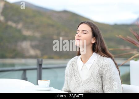 Ragazza rilassato respirando aria fresca con gli occhi chiusi in una caffetteria e terrazza Foto Stock