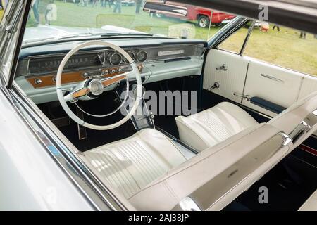 Vista interna di un'auto americana d'epoca con sedili bianchi classici e cruscotto retrò in una mostra di auto all'aperto Foto Stock