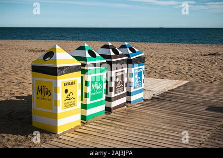 Riga di coloratissimi cestini per la raccolta differenziata e il riciclaggio a La Cala de Mijas beach, Costa del Sol, Spagna. Foto Stock