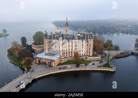 Antenna fuco shot vista di Schwerin Palace castello con pesanti haze di nebbia al mattino dal lago Schwerin Foto Stock