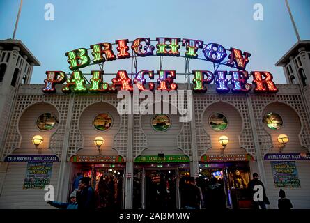 Il colorato segno illuminato del Brighton Palace Pier è illuminato al tramonto. Il famoso molo sul mare di Brighton, uno dei tour più popolari del Regno Unito Foto Stock