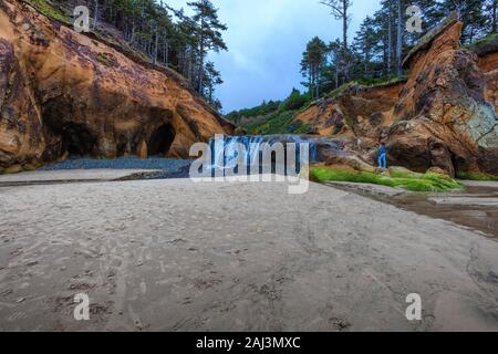 Gli adolescenti esplorare intorno al punto di abbraccio cascate a bassa marea sulla costa dell'Oregon. Foto Stock