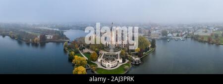 Antenna fuco shot vista di Schwerin Palace castello con haze nebbia oltre il suo parco giardino del lago Schwerin Foto Stock