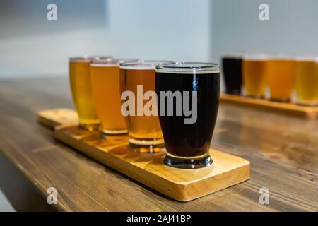 Volo di craft di quattro diversi tipi di birra bicchieri di birra nera su un vassoio di legno durante una sessione di degustazione di close-up di messa a fuoco selettiva con spazio di copia Foto Stock