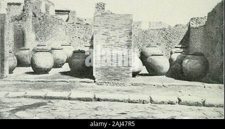 Pompéi : vie publique . Fig. 6j. - Doliams de marchands dhuile et autres denrées (p. 123). tique, il savon naturel, avec laquelle les étoffes étaient nettoyées ; su seservait aussi, pour cet usage, durine ou de potasse. La foulerie quenous représentons ici iig. 66, p. 123; est celle de la rue de Stabies;cest une maison particulière transformée en foulerie. Après avoir traverséson joli atrium qui a conservé, dans limpluvium, la vasque, la base dela statua-fontaine et le cartibulum, su rencontre Au delà du tablinum, aulieu du Jardin, les longues cuves et les endroits où su foulait. Sur le mur degau Foto Stock