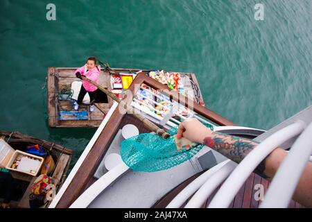 Vendite flottante persone avvicinando le navi da crociera che vendono merci - la Baia di Ha Long, Ha Long, Vietnam Foto Stock