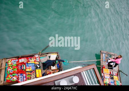 Vendite flottante persone avvicinando le navi da crociera che vendono merci - la Baia di Ha Long, Ha Long, Vietnam Foto Stock