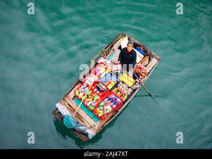 Vendite flottante persone avvicinando le navi da crociera che vendono merci - la Baia di Ha Long, Ha Long, Vietnam Foto Stock