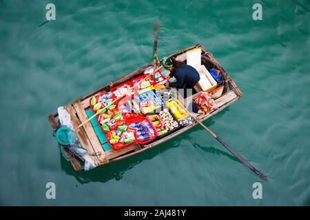 Vendite flottante persone avvicinando le navi da crociera che vendono merci - la Baia di Ha Long, Ha Long, Vietnam Foto Stock