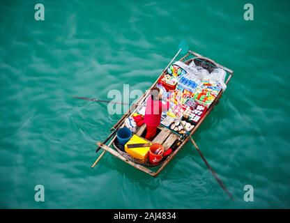 Vendite flottante persone avvicinando le navi da crociera che vendono merci - la Baia di Ha Long, Ha Long, Vietnam Foto Stock