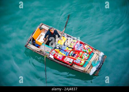 Vendite flottante persone avvicinando le navi da crociera che vendono merci - la Baia di Ha Long, Ha Long, Vietnam Foto Stock