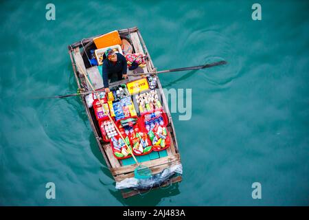 Vendite flottante persone avvicinando le navi da crociera che vendono merci - la Baia di Ha Long, Ha Long, Vietnam Foto Stock