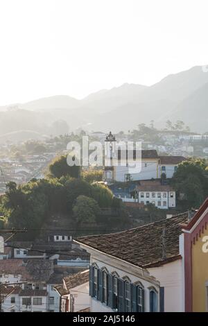 Vista sopra la città coloniale di Ouro Preto, Minas Gerais, Brasile, con una chiesa bianca su una collina. Foto Stock