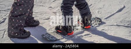 La Madre insegna il figlio lo snowboard. Attività per bambini in inverno. Bambini sport invernali. Stile di vita banner, formato lungo Foto Stock