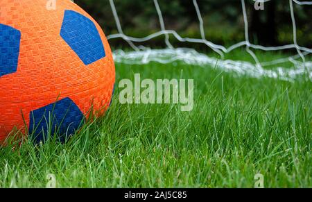Close up di orange pallone da calcio in erba con sfondo netto Foto Stock