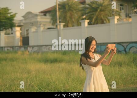 Ritratto di giovane bella donna asiatica nel campo di girasoli in fiore Foto Stock