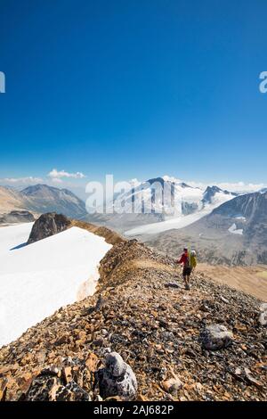 Vista posteriore del escursionista che attraversa crinale roccioso in giornata di sole. Foto Stock