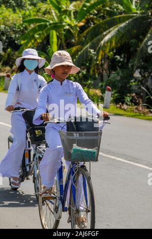 Delta del Mekong, Vietnam; 10 ottobre 2005. Scolare il ciclismo Home dalla scuola indossando divise tradizionali. Foto Stock