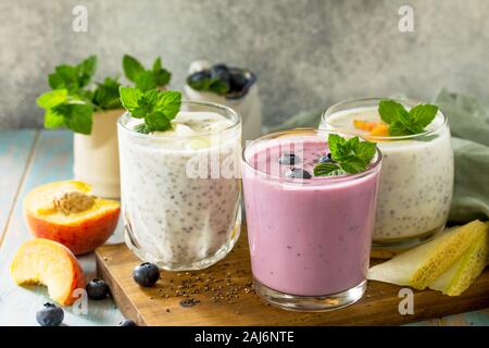 Un sano Chia set. Il budino in un bicchiere con mirtillo, con melone e pesca in legno tavolo da cucina. Una sana prima colazione, vitamina snack, dieta e sana Foto Stock