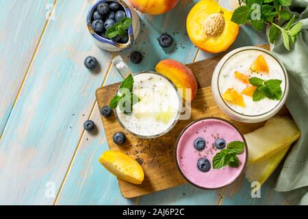 Un sano Chia set. Il budino in un bicchiere con mirtillo, con melone e pesca in legno tavolo da cucina. Una sana prima colazione, vitamina snack, dieta e sana Foto Stock