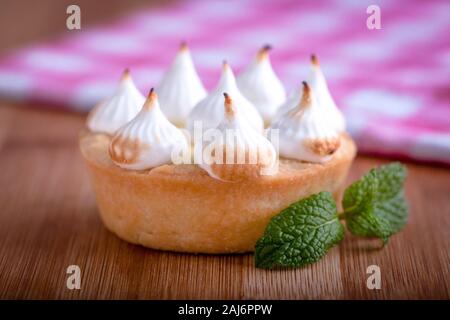 Elegante tortine con limone e curda meringa bruciata dal una fiamma. Molto gustosi tortini. Tartlet riempito con crema di limone (curdo) e meringa Foto Stock