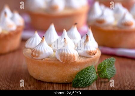 Elegante tortine con limone e curda meringa bruciata dal una fiamma. Molto gustosi tortini. Tartlet riempito con crema di limone (curdo) e meringa Foto Stock