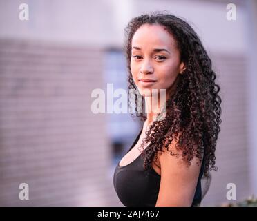 Foto di una ragazza nera con i capelli lunghi e posa di indossare abbigliamento sportivo. Fitnessd di indossare abbigliamento sportivo. Centro fitness Foto Stock