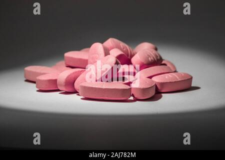 Close-up foto di alcune pillole rosa con direct yellow studio luce Foto Stock