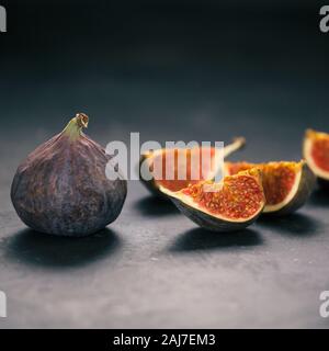 Fichi freschi, fotografia creativa, tagliere di legno, succosa fresche, sfondo scuro Foto Stock