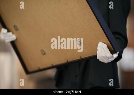 Close-up di donna in costume nero che indossa guanti bianchi e azienda grande dipinto a mano Foto Stock