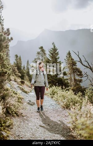 donna che indossa camice bianco escursioni sul sentiero nel parco del ghiacciaio montana Foto Stock