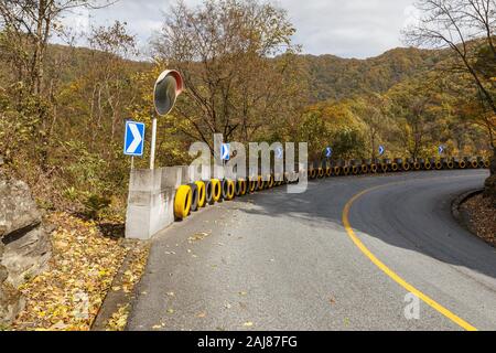 Strada asfaltata nelle montagne della Cina, specchio convesso e ruote vettura per la sicurezza. Foto Stock