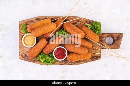 Tradizionali di mais americano cani con mostarda e ketchup sulla tavola di legno. Cucina di strada. Vista superiore, spazio di copia Foto Stock