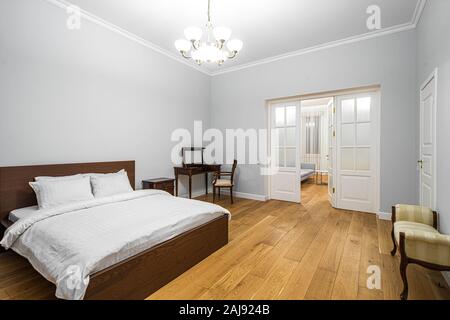 Interni moderni e di lusso spaziosa camera da letto. Il letto king size. Arredi in legno. Porta bianca. Foto Stock