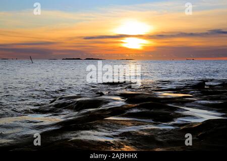 Inverno tramonto al litorale roccioso di Uunisaari Isola, Helsinki, Finlandia. Foto Stock