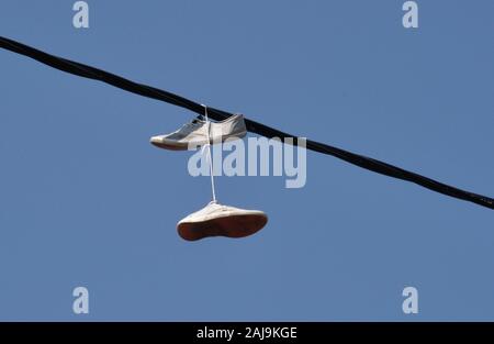 Scarpe attaccato ad un filo elettrico mediante i lacci Foto Stock